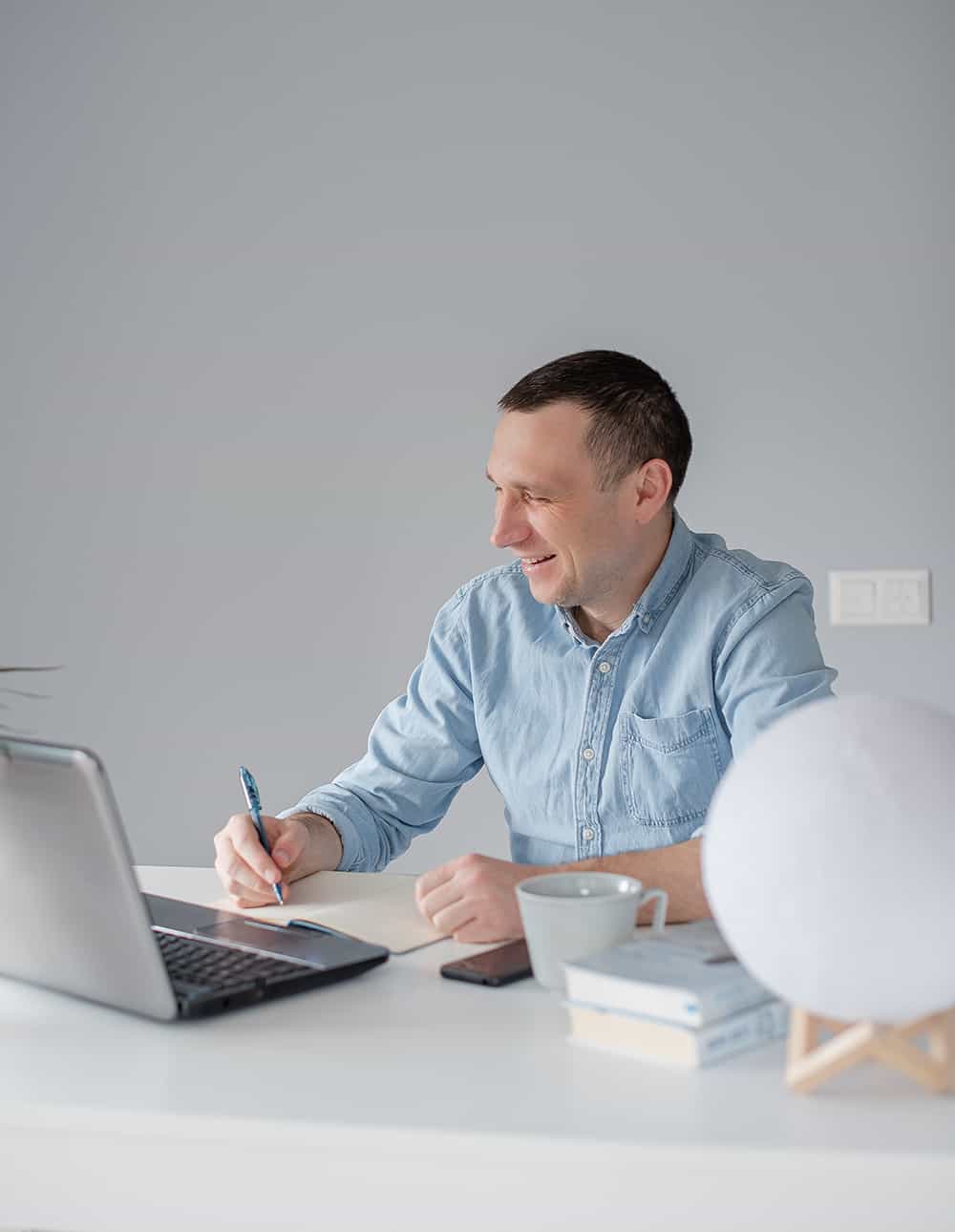 young-man-sitting-at-work-desk-at-home-remote-work-AYYPH67